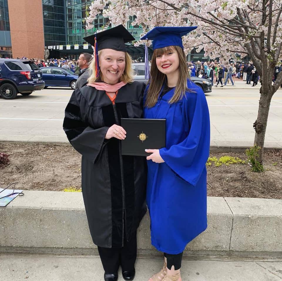 Lauren Glomb holding her GVSU diploma, standing next to Dr. Vavrikova.